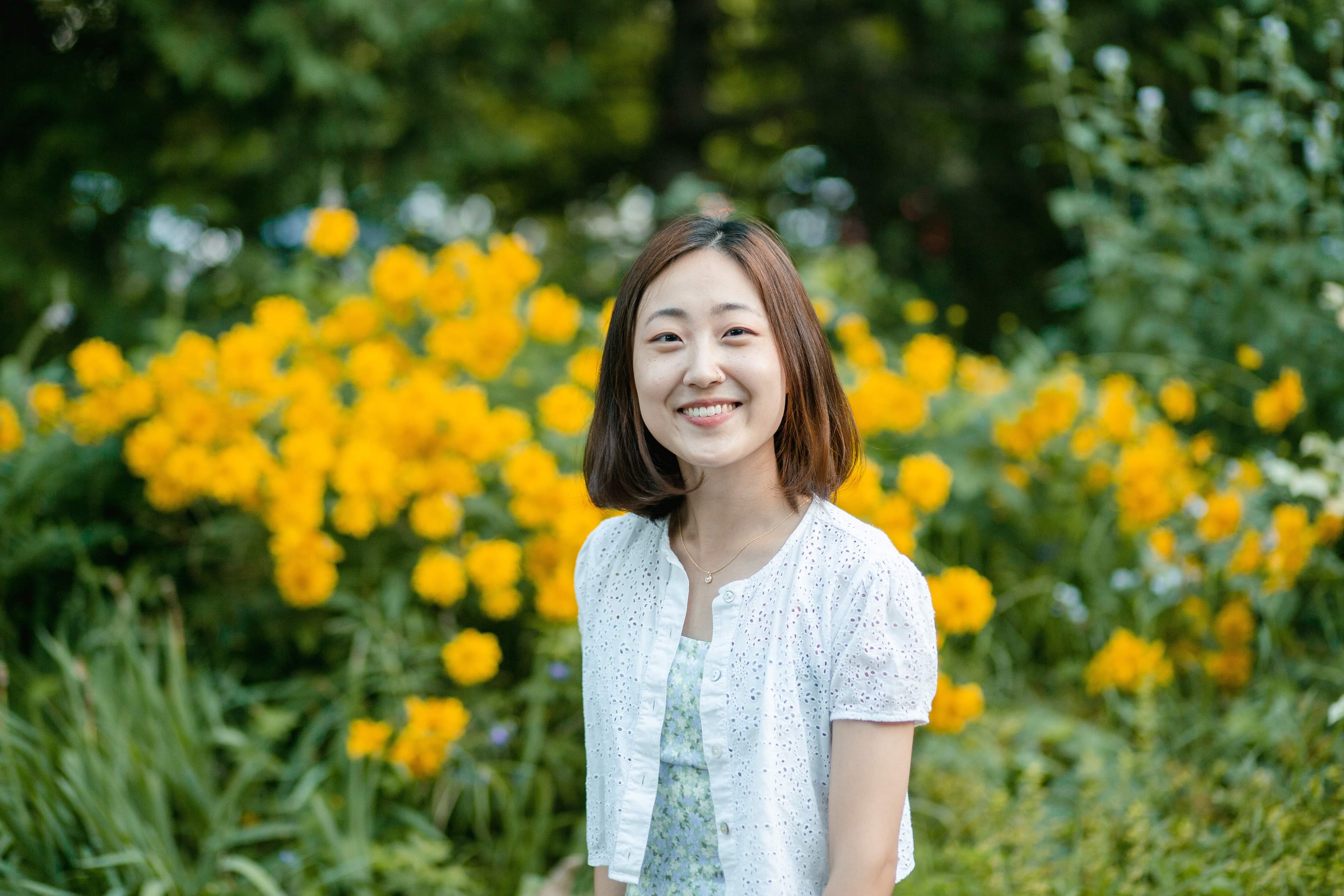 Ashley Chung smiling outdoors in front of yellow flowers