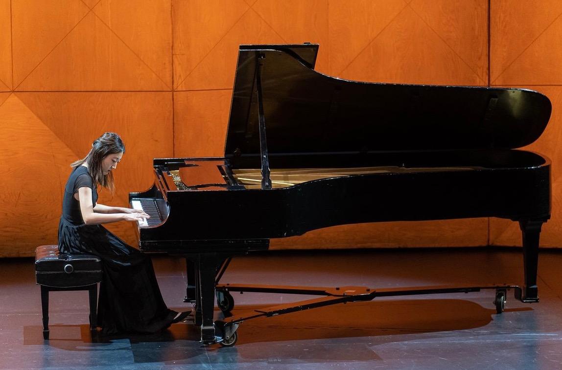 Ashley Chung performing on a grand piano in a concert hall